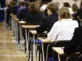 Uczniowie siedzą w rzędach przy ławkach, skupieni na rozwiązywaniu pytań maturalnych.