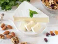 Queso brie en cuña y trozos, decorado con menta. Alrededor hay almendras, nueces y frutos secos. Ideal para quienes buscan información sobre queso brie calorias.