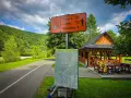 Znak drogowy dla rowerzystów na szlaku Velo Sola. Wskazuje kierunki i odległości do Żywca, Ciśca i Milówki. Obok mapa szlaku.