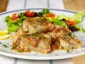 Deliziosa coda di rospo in umido con pomodoro e prezzemolo, servita con insalata fresca e spicchi di limone.