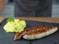 Zwei goldbraune Bratwürste mit Kartoffelsalat, perfekt für alle, die Bratwurst selber machen wollen.