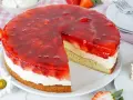 Ein saftiger Erdbeerkuchen mit Pudding, Sahne und einer glänzenden Erdbeer-Gelee-Schicht. Ein Stück fehlt bereits.