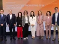 Presentación del código de ética de una empresa. Un grupo de siete profesionales posa en un escenario con un fondo naranja y blanco.