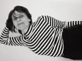 Katarzyna Krzanowska w czarno-białym swetrze w paski, leżąca na boku, z ręką pod głową.