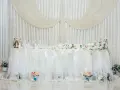 Elegancka ścianka za parą młodą inspiracje: białe zasłony, kwiaty, napisy "Wedding", "Love", "Mrs & Mr".