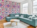 Un salon moderne avec un canapé bleu sarcelle et un papier peint intissé aux motifs ethniques colorés.