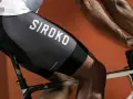 En cyklist med synliga cykling muskler på benen, klädd i svarta cykelbyxor med texten "SIROKO".