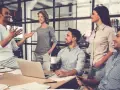 Un gruppo di persone in un ufficio moderno discute animatamente. I colleghi non sono amici, ma lavorano insieme con professionalità.