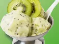 Erfrischendes Kiwi-Eis in einer Schale, garniert mit frischen Kiwischeiben. Ein Löffel steckt darin, bereit zum Genuss.