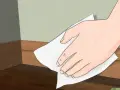 Mano limpiando rodapiés de pintura con un paño blanco.