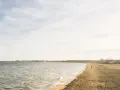 Spokojny dzień nad morzem na Kaszubach. Pusta plaża, delikatne fale i kilka osób spacerujących brzegiem.