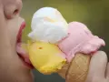 Eiscreme-Liebhaberin schleckt an einem Eis mit drei Kugeln. Die richtige guarkernmehl dosierung macht das Eis cremig.