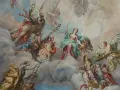 Deckenmalerei mit vielen geflügelten Figuren, die durch Wolken schweben. Eine Frau mit Waage wirkt wie ein engel auf erden.