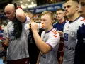 Szymon Adamczyk pije wodę z bidonu, otoczony kolegami z drużyny.