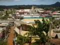 Vue d'une ville aux Comores, Mayotte, avec des maisons colorées, des bananiers et une montagne en arrière-plan.