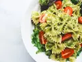 Pyszna sałatka z makaronem farfalle w sosie pesto, z pomidorkami koktajlowymi i świeżą sałatą.