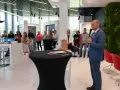 Mężczyzna w garniturze przemawia do grupy osób w nowoczesnym salonie okien i drzwi.