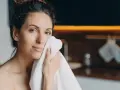 Une femme se sèche le visage avec une serviette. Elle a une peau radieuse, peut-être grâce aux 10 aliments bon pour la peau.