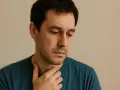 Uomo pensieroso, con mano sul collo, sembra voler evitare lo sguardo, significato di introspezione o disagio.