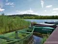 Zielone łodzie przy pomoście, idealne na wyprawę po jeziorach. Suwalszczyzna atrakcje czekają!