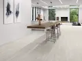 Elegantes suelos para cocinas blancas con un diseño moderno y minimalista, que complementan la isla de madera y las sillas altas.