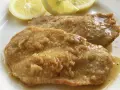 Deliziose scaloppine al limone, succulente e dorate, servite con spicchi di limone fresco.