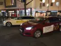 Ein weißes Taxi und ein rotes Auto mit Uber-Werbung stehen nebeneinander. Der Unterschied über Taxi ist die moderne Alternative.