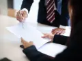 Biznesmeni omawiają dokumenty, analizując opłatę stosunkową.