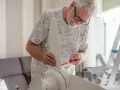 Hombre mayor instala un ventilador de techo pladur con un destornillador.