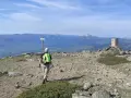 Senderista camina hacia el **puerto de Navafría**, con un mojón y montañas nevadas al fondo.