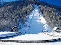 Zimowa Planica w Alpach Julijskich, z ośnieżoną skocznią narciarską i lasem iglastym.