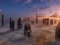 Wieżowce w Dubaju, w tym najwyższy budynek świata, wyłaniają się z mgły o wschodzie słońca.