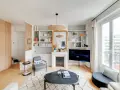 Aménagement entrée ouverte avec rangements boisés, fauteuil, cheminée décorative et étagères remplies de livres.