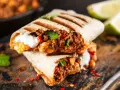 Pyszne burrito przepis: soczyste mięso mielone, ciecierzyca, papryczka chili i śmietana, podane na desce.