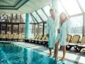 Para na weekend w spa. Para w szlafrokach przy basenie, ciesząca się słońcem i relaksem.