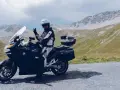 Motocyklista w kasku pozdrawia na tle gór. Przełęcz Stelvio zamknięta, ale widoki zapierają dech w piersiach.