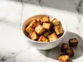 Chrupiące kostki tofu z airfryera w miseczce, idealne do sałatki lub jako przekąska.