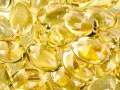 En hög med genomskinliga, gulaktiga kapslar som liknar solens strålar. Dessa kan vara vitaminer som ger energi.