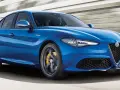 Błękitne Alfa Romeo Giulia Veloce pędzi po drodze, ukazując sportowy charakter i dynamiczną sylwetkę.