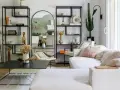 Soggiorno con divano bianco, librerie nere, specchio ad arco e cactus. Un'oasi di pace in stile casa minimal.