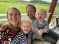 Familj med barn på en altan med grönskande landskap i bakgrunden. En härlig stund med norge med barn.