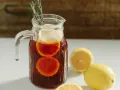 Dzbanek orzeźwiającej sangrii wino z plasterkami pomarańczy i cytryny, ozdobiony gałązką rozmarynu.