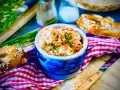 Herzhaftes Obazda-Rezept in einem blauen Steingut-Töpfchen, garniert mit Schnittlauch und Paprikapulver, daneben Brezeln und ein Messer.
