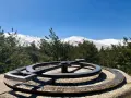 Un mirador de la gitana con un compás de bronce y montañas nevadas al fondo.