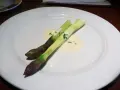 Zwei Spargelstangen auf einem Teller, serviert mit einer cremigen beurre blanc Sauce und gehackten Kräutern.