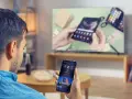 Mann verbindet sein Handy mit dem Fernseher, um ein Video anzusehen. Auf dem Handy ist ein YouTube-Video zu sehen.