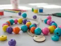 Färgglada träpärlor och pysselmaterial ligger utspridda, redo för att måla med barn. En härlig aktivitet för kreativa stunder.