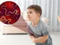 Chłopiec trzyma się za brzuch, a powiększenie pokazuje glistę ludzką. Objawy mogą być niepokojące.