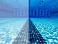 Underwater view of a swimming pool, half clear and half cloudy, with lane lines and lane markers.