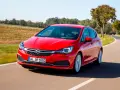 Czerwony Opel Astra jedzie po krętej drodze. W tle pola i drzewa. Idealny do diagnostyki z **op-com opel po polsku**.